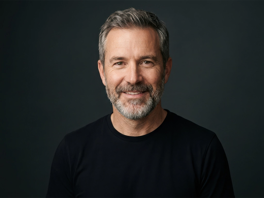 handsome middle aged man with gray hair and beard smiling at camera